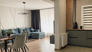 Ένα σύγχρονο σαλόνι με τραπεζαρία, κουζίνα και ένα μεγάλο παράθυρο με περσίδες.