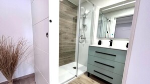 Un bagno moderno con box doccia in vetro, una parete decorata in legno e un mobile vanitario con specchio.