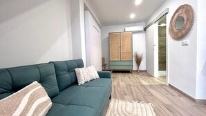 Un soggiorno moderno con un divano verde, un tappeto decorato e un pavimento in legno.