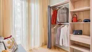 Een slaapkamer met een bed, een kledingkast en een raam met dunne gordijnen.