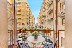 A balcony with a table and chairs, overlooking a street with parked cars and buildings. - Cinque Terre The Galleria Apartment (La Spezia)