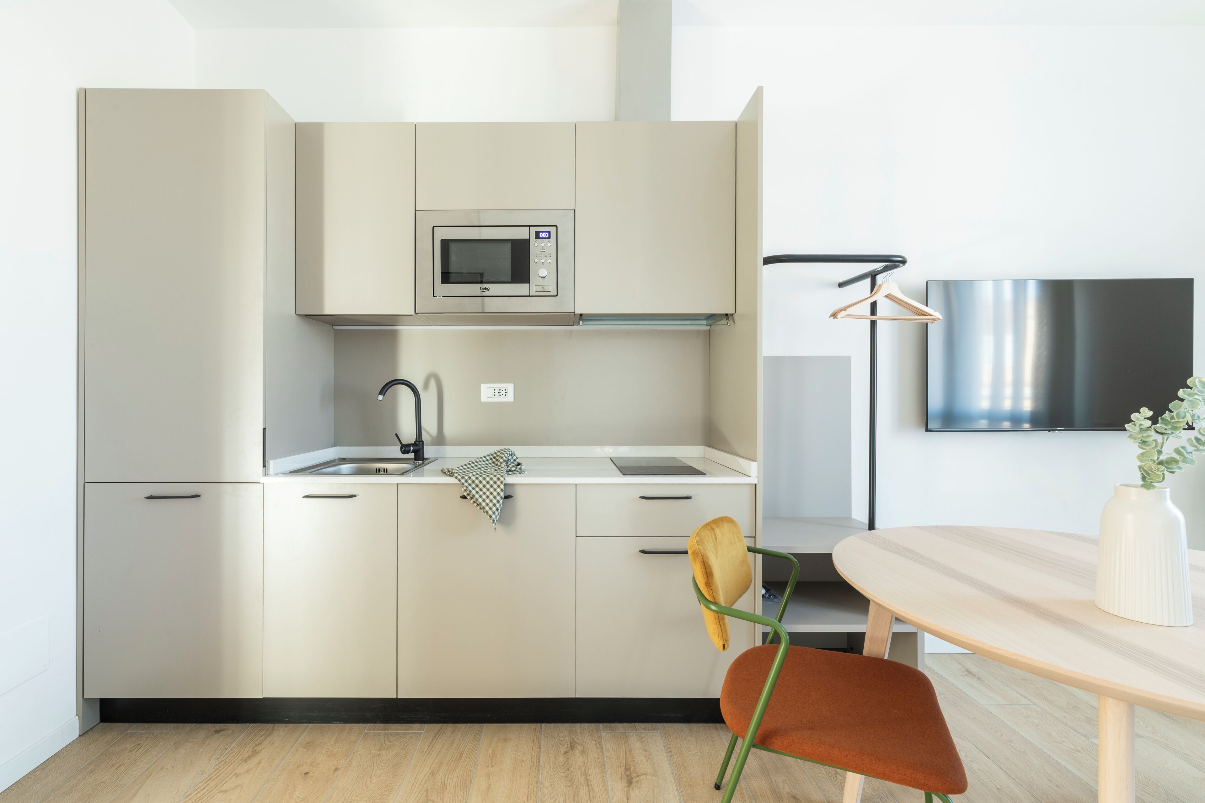 A modern kitchen with a microwave, sink, and a wooden dining table with a chair.