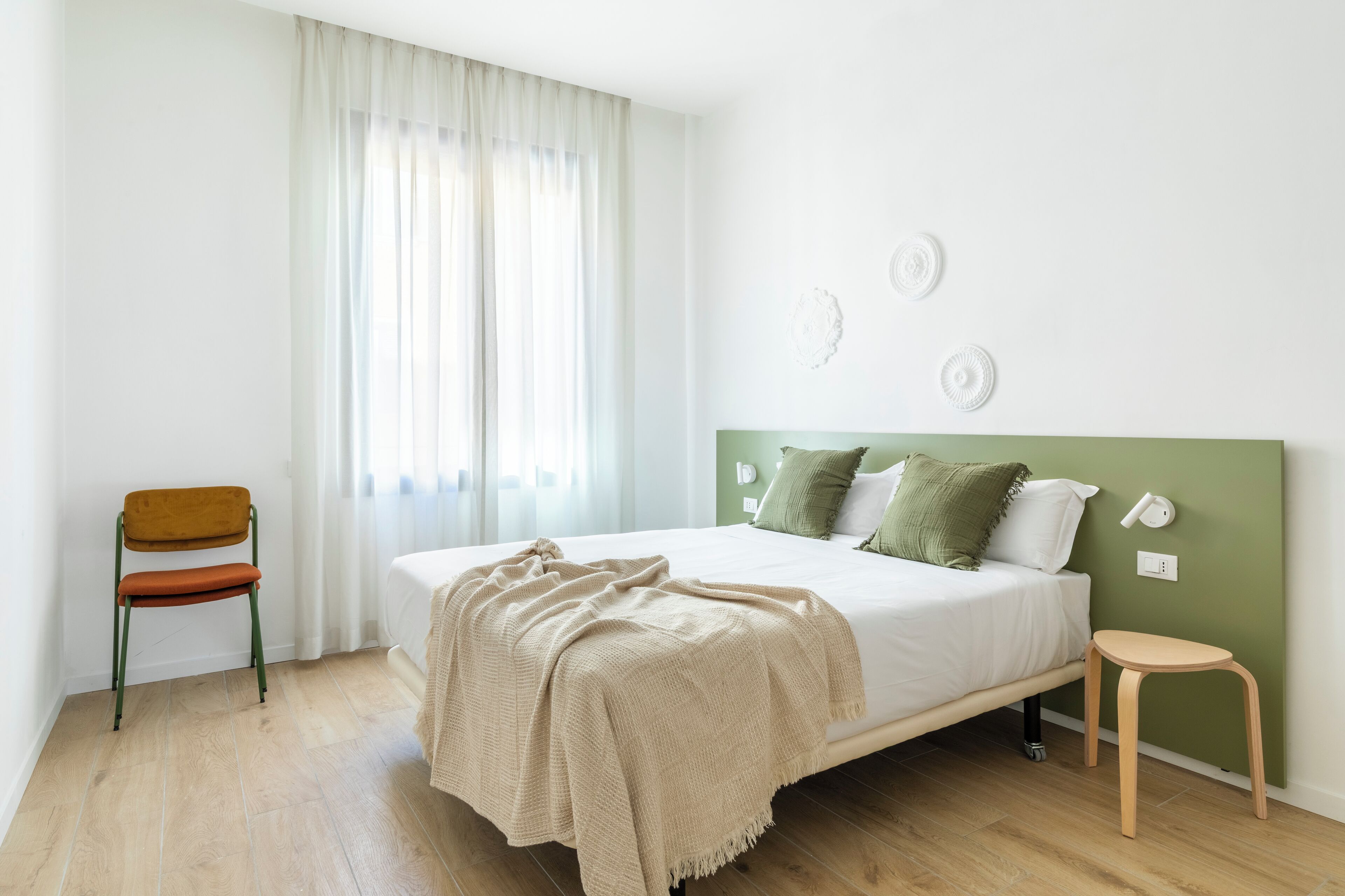 Une chambre à coucher avec un lit, une chaise et un petit tabouret.