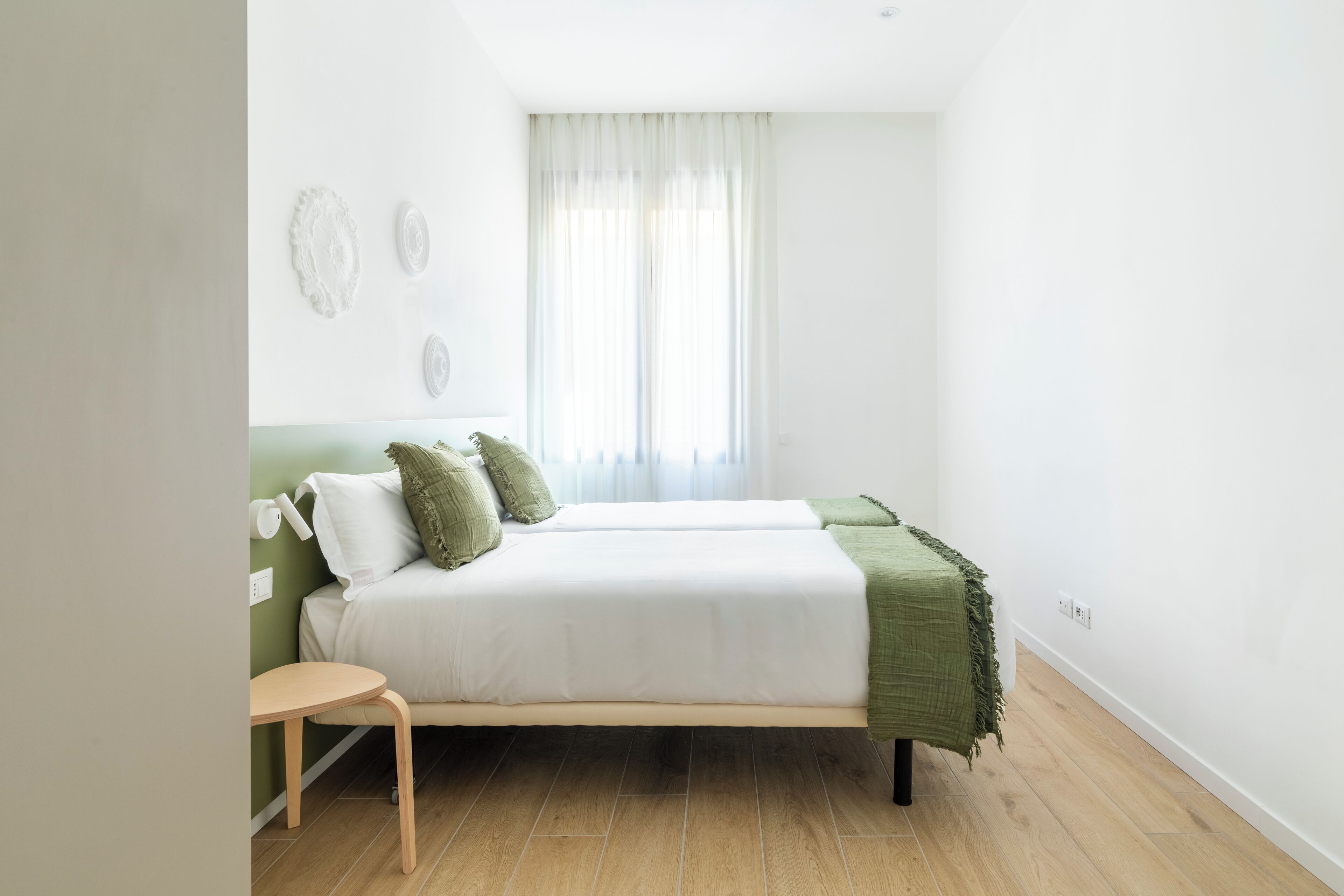 Ein Schlafzimmer mit einem Bett, einem kleinen Tisch und einem Fenster mit Vorhängen.