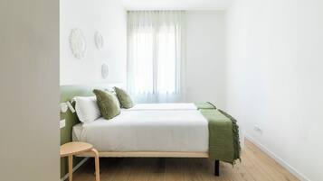 Ein Schlafzimmer mit einem Bett, einem kleinen Tisch und einem Fenster mit Vorhängen.