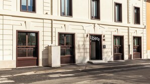 A building with multiple windows and doors, including a prominent entrance with a sign that reads "libere". - Líbere Rome San Lorenzo (Rome)