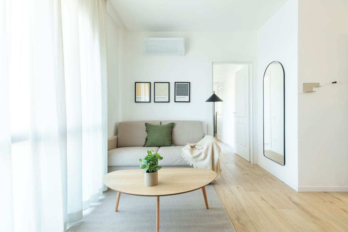 A modern living room with a sofa, a coffee table with a plant, and framed pictures on the wall.