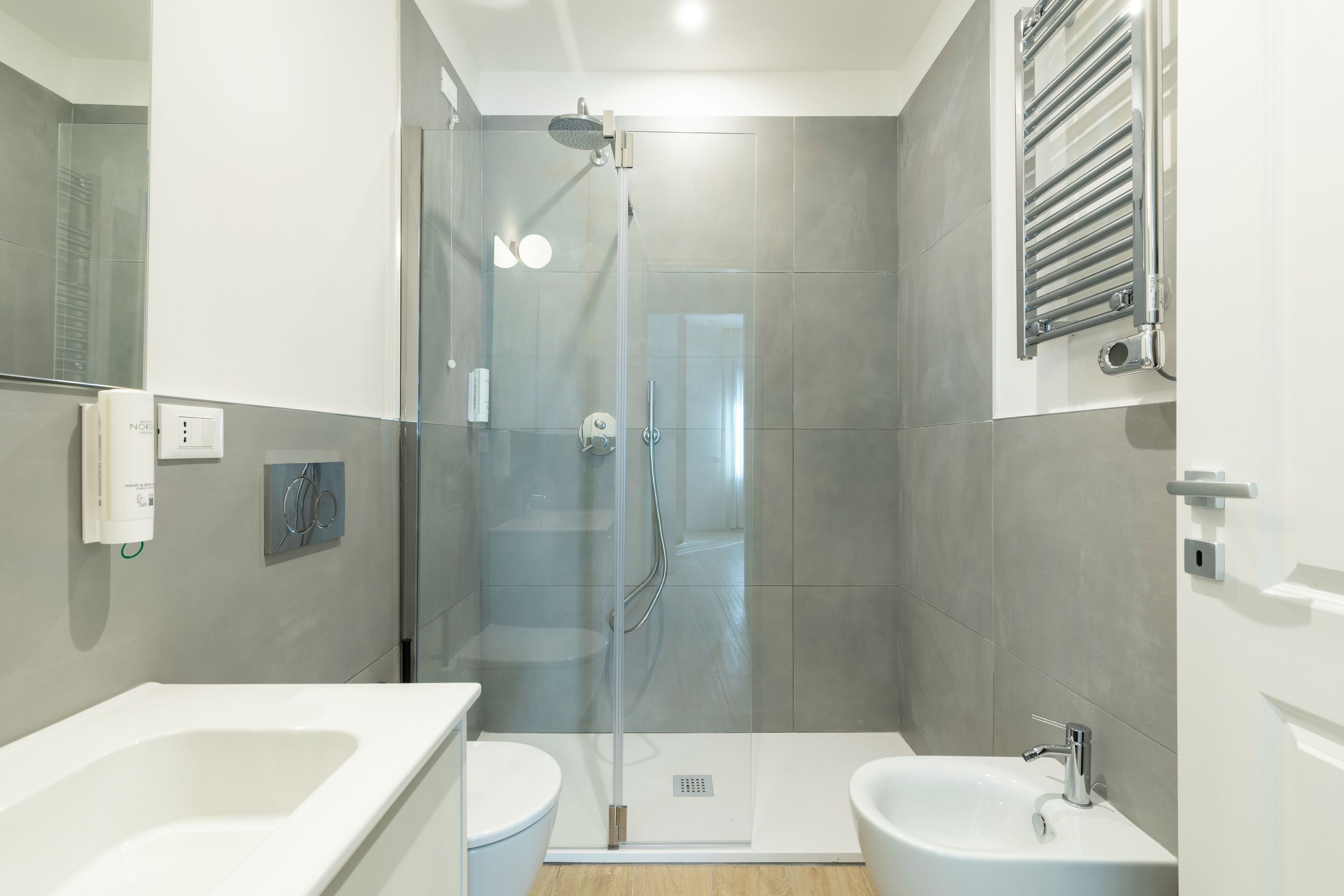 Ein modernes Badezimmer mit einer Glaskabine zur Dusche, einem weißen Waschbecken und einem Bidet.