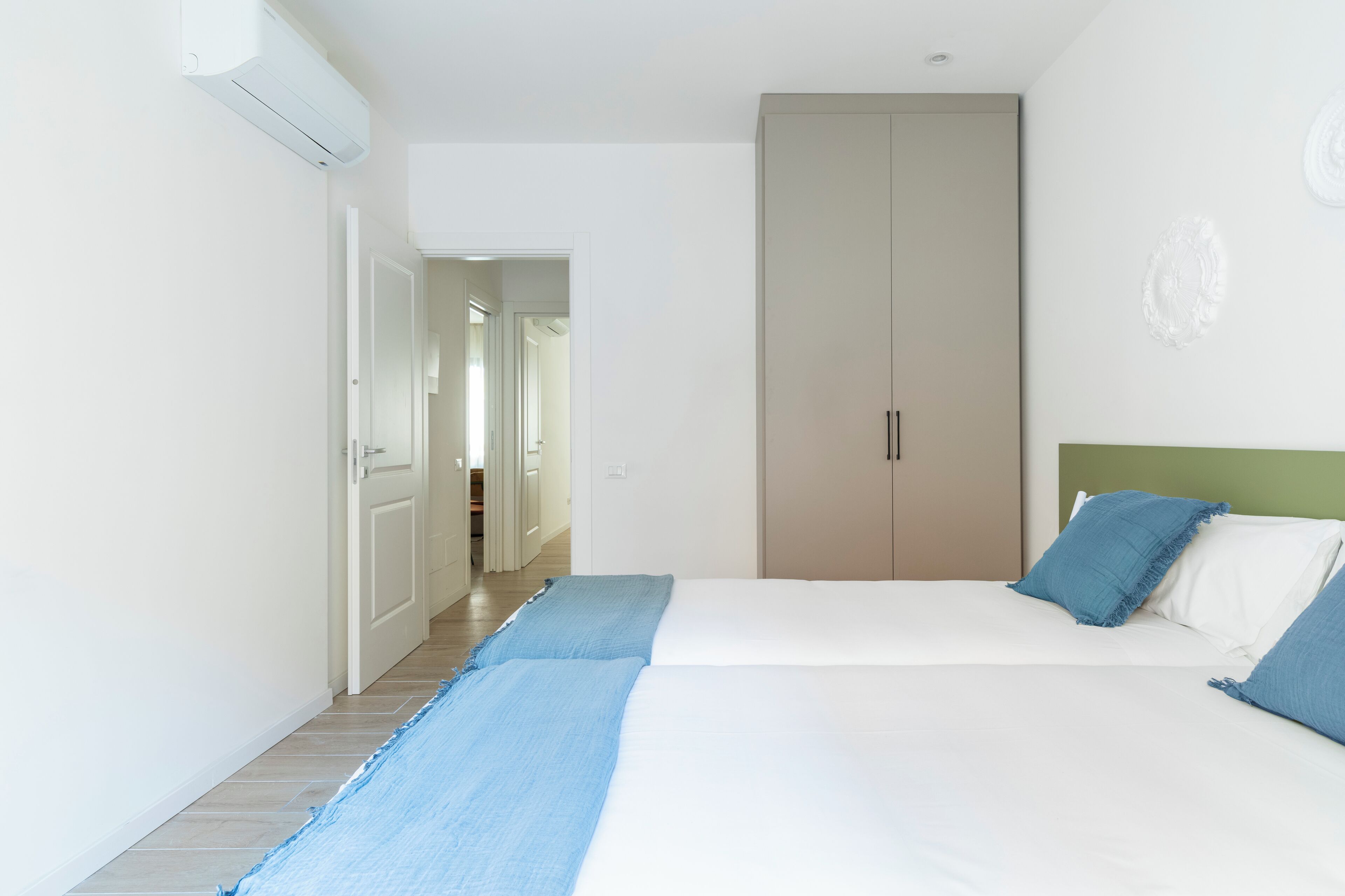 Un dormitorio con cama, un armario y un pasillo que conduce a otra habitación.