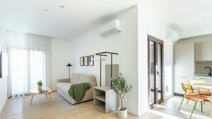 A modern living room with a sofa, a small table with a plant, a floor lamp, and a dining area with chairs. - Líbere Rome San Lorenzo (Rome)