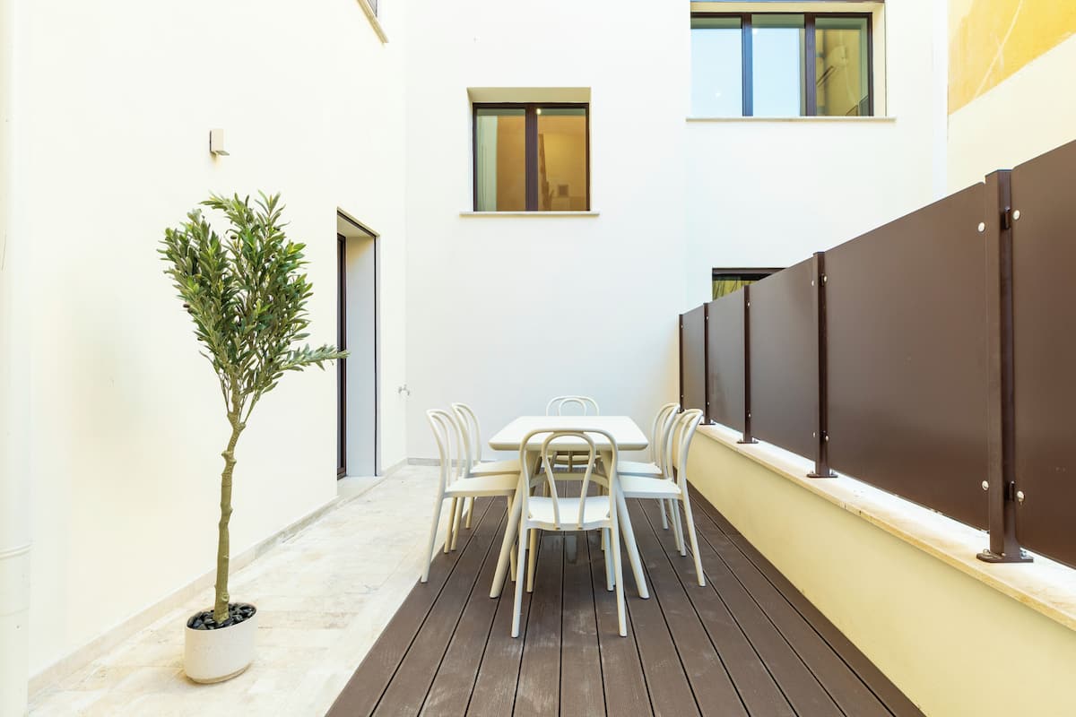 A patio with a table and chairs, a potted plant, and a wooden deck.