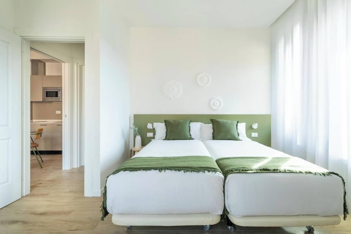 A double bed with a green headboard, a small bedside table, and a wall-mounted light fixture.