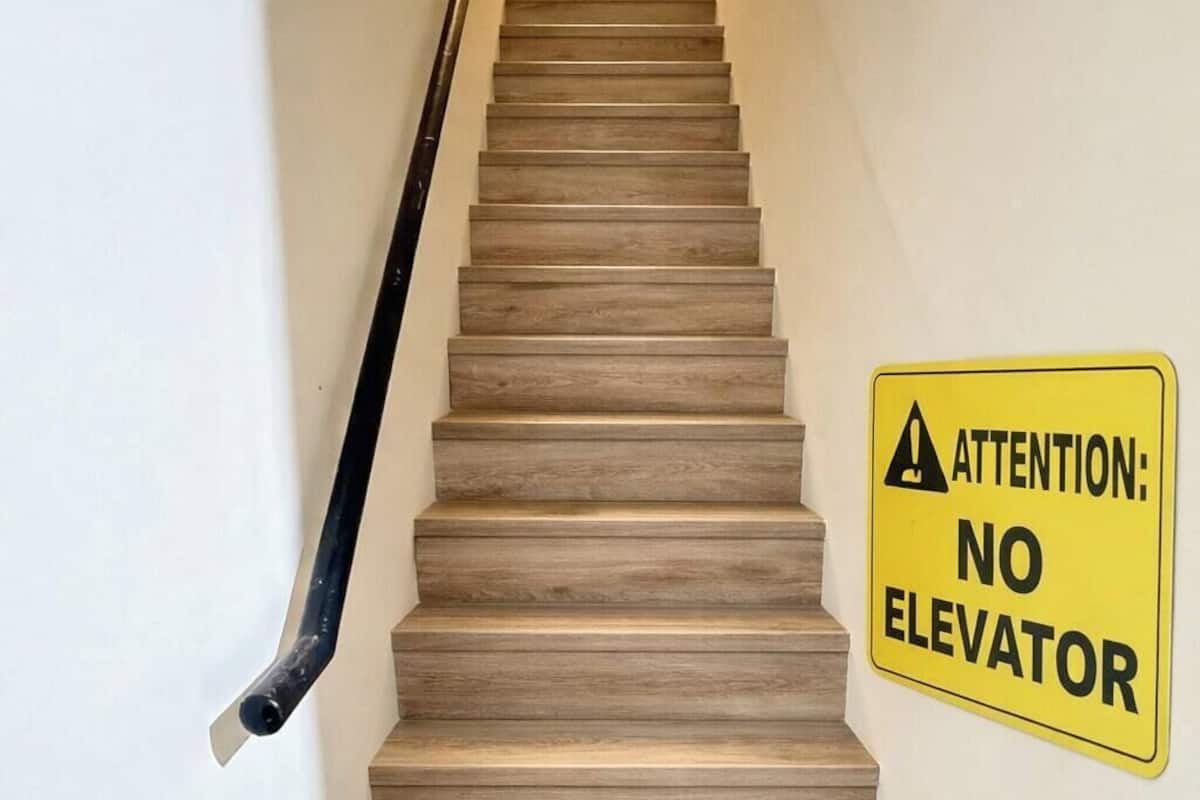 A staircase with a yellow caution sign stating "ATTENTION: NO ELEVATOR".