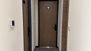 A hallway with a wooden door marked "1201", a security camera, and a light fixture on the ceiling. - 35APT- Self Check In (Taipei)