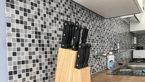 Une cuisine avec un mur recouvert de carreaux, un bloc à couteaux en bois, un évier et une bouteille de liquide vaisselle.