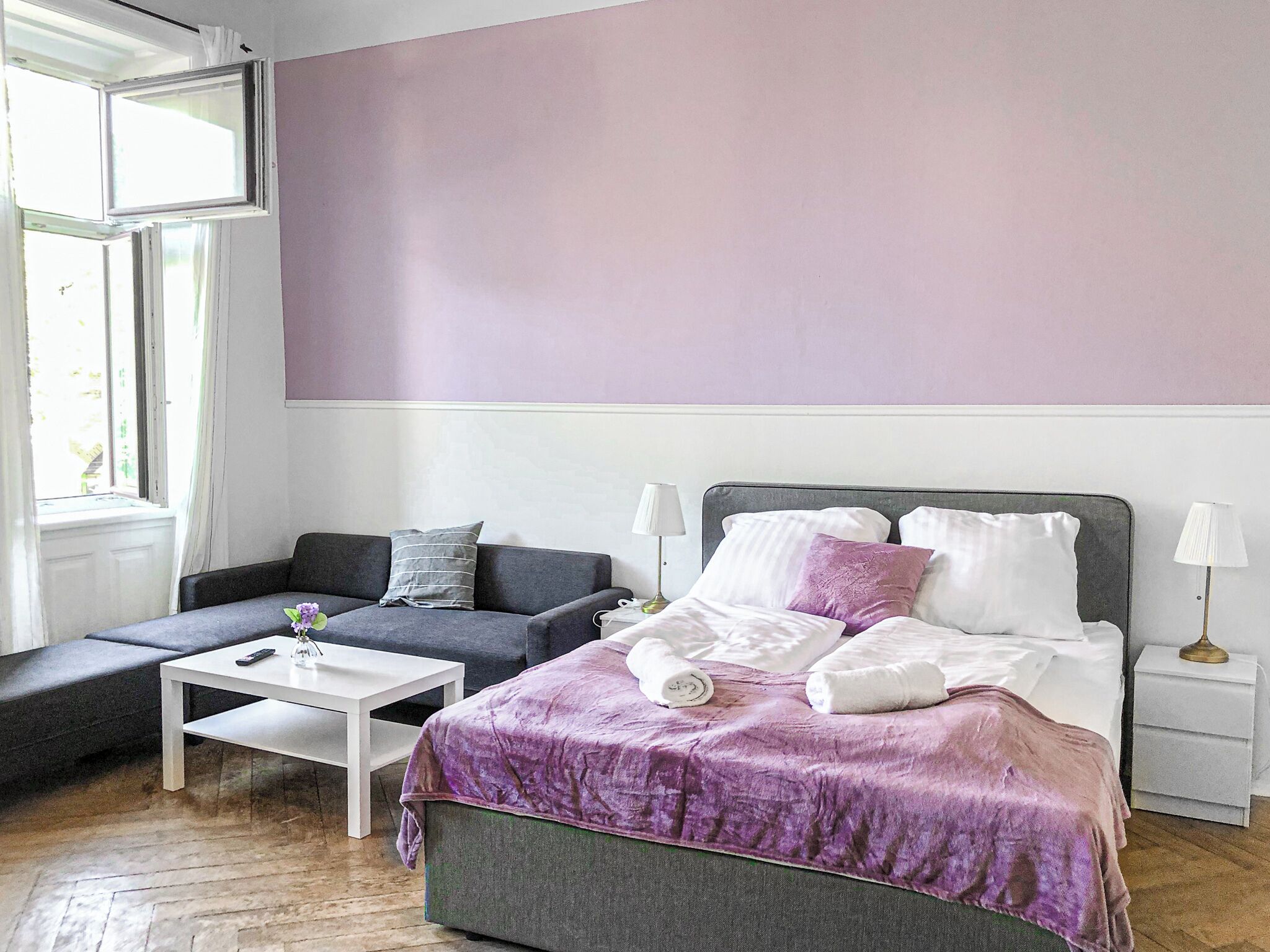 Ein modernes Schlafzimmer mit einem Bett, einer Couch, einem kleinen Tisch und einem Nachttisch.