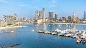 A marina with yachts docked, a bridge, and a city skyline with modern skyscrapers. - StayShort - Elegant 1 Bedroom in EMAAR Beachfront that Sleeps 2 (EMAAR Beachfront)