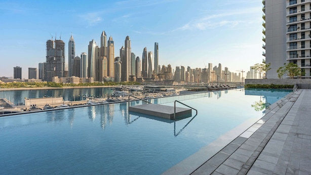 A modern hotel with a rooftop infinity pool overlooking a city skyline. - StayShort - Elegant 1 Bedroom in EMAAR Beachfront that Sleeps 2 (EMAAR Beachfront)