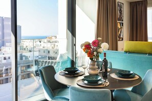 A dining area with a table set for two, a vase of flowers, and a bottle of wine. - Mercury Tower (St. Julian's)