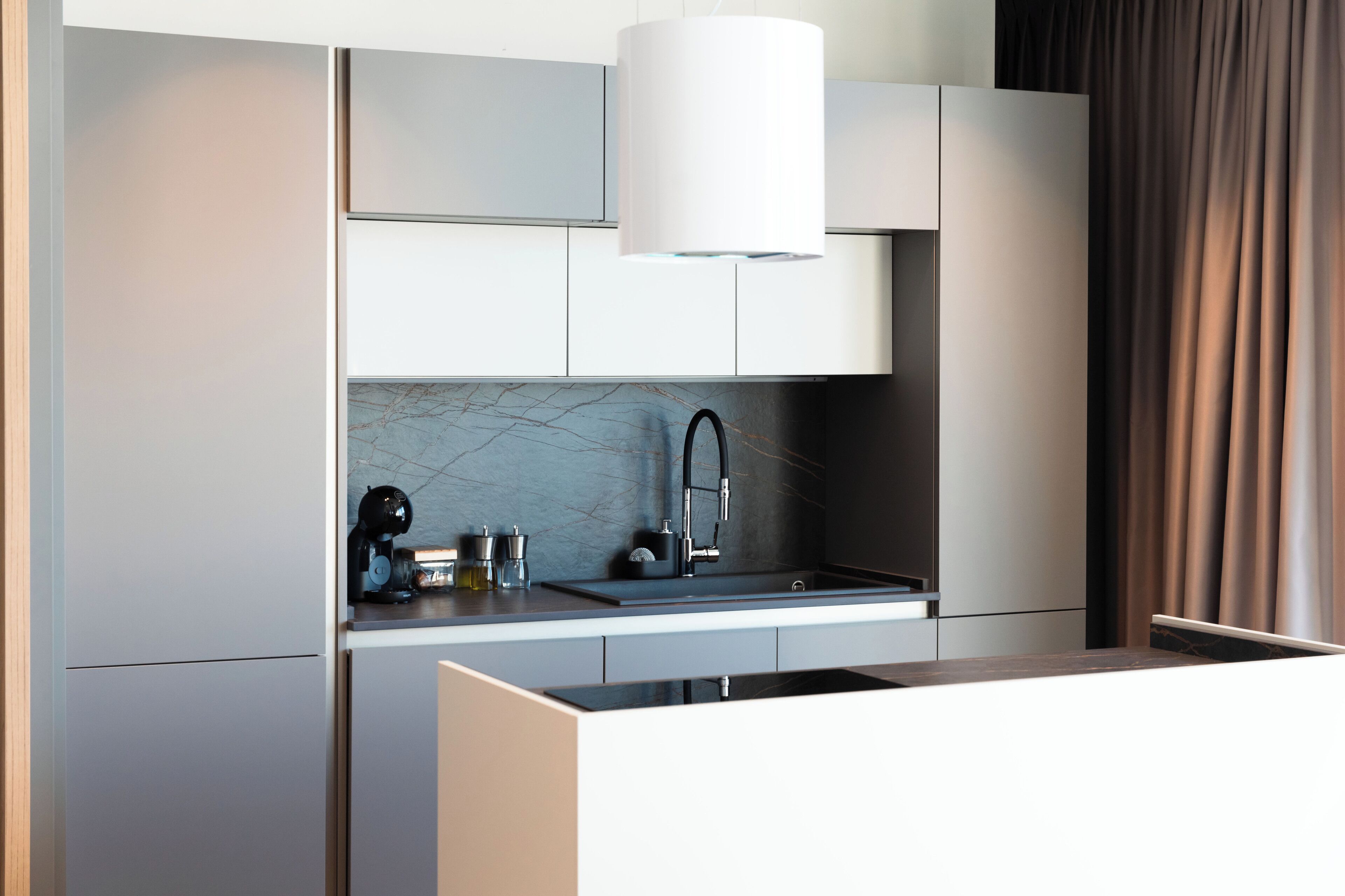 A modern kitchen with a built-in stove, a sink, and a large overhead light.