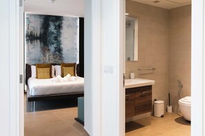 A modern hotel room with a bed, a bathroom with a sink and toilet, and a large abstract painting on the wall. - Mercury Tower (St. Julian's)