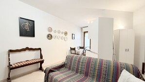 Et værelse med seng, bænk, sofa, garderobe og spiseplads.