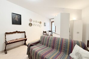 Una stanza con un letto, una panca, un divano, un armadio e un'area pranzo.