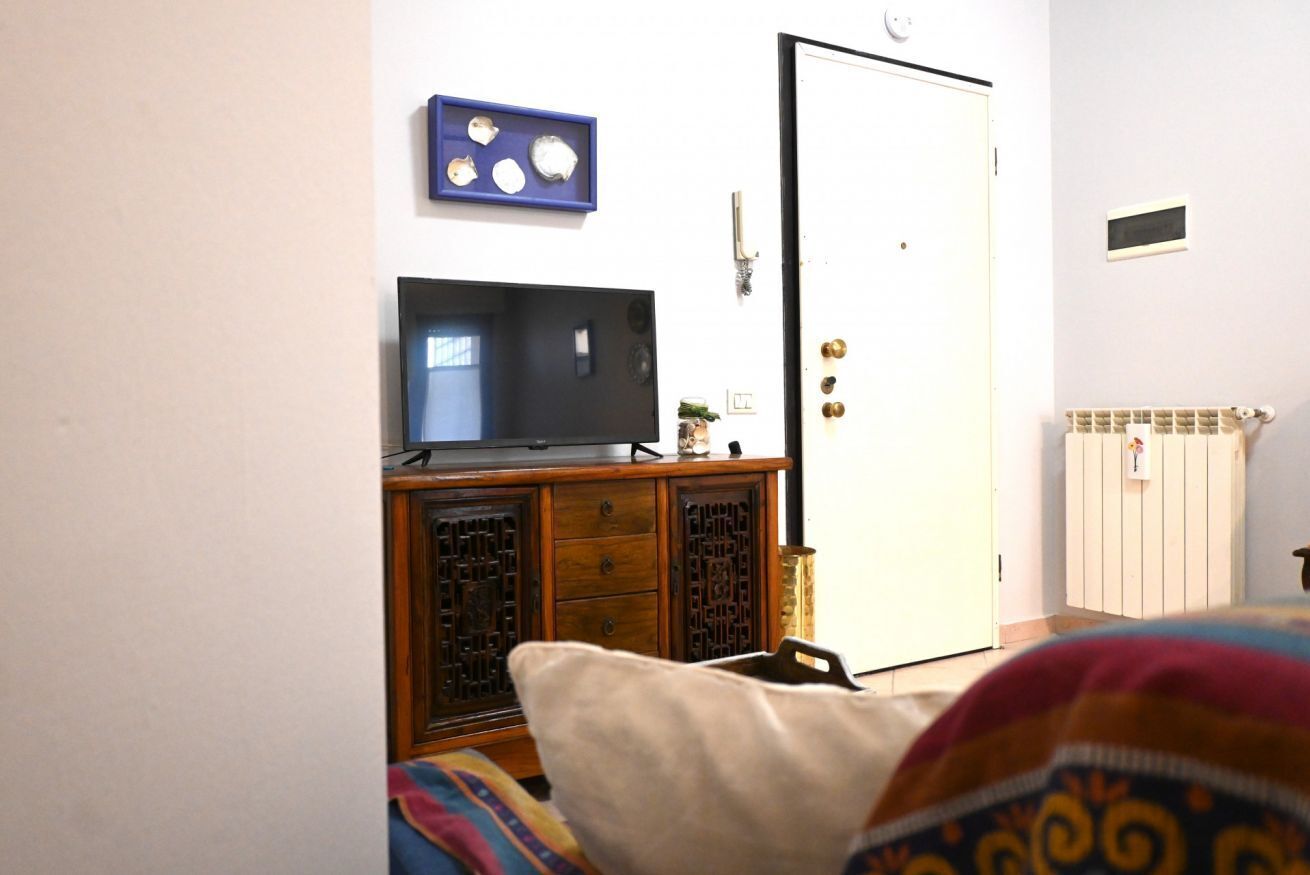 A room with a television on a wooden cabinet, a door, and a radiator.