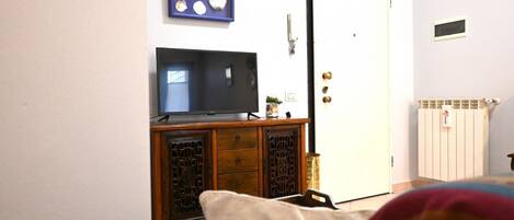 A room with a television on a wooden cabinet, a door, and a radiator.
