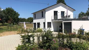 Et moderne hus med to etager, en altan, en belagt indkørsel og en have.