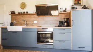 A modern kitchen with a built-in oven, a coffee maker, and a clock on the wall. - Holiday Apartment Im Weiler, 70m², 1 Bedroom, Up to 4 Guests (Winterlingen)