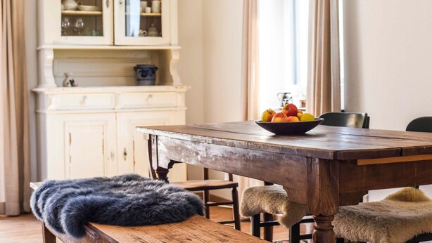 A dining table with a bowl of fruit, a fur throw, and a vintage lamp. - Holiday Apartment Im Weiler, 70m², 1 Bedroom, Up to 4 Guests (Winterlingen)