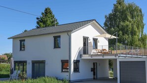 A modern two-story house with a balcony, a garage, and a paved driveway. - Holiday Apartment Im Weiler, 70m², 1 Bedroom, Up to 4 Guests (Winterlingen)