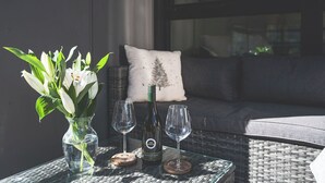 Un vase en verre contenant des fleurs blanches, une bouteille de vin et deux verres à vin, le tout posé sur une table.