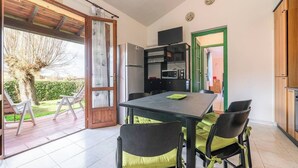 Une cuisine avec un coin repas, un téléviseur et une porte donnant sur un jardin.