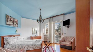 Ein Schlafzimmer mit Bett, Nachttisch und an der Wand montiertem Fernseher.
