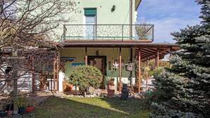 Ein zweistöckiges Gebäude mit Balkon, Blumentöpfen und einem kleinen Baum im Hof.