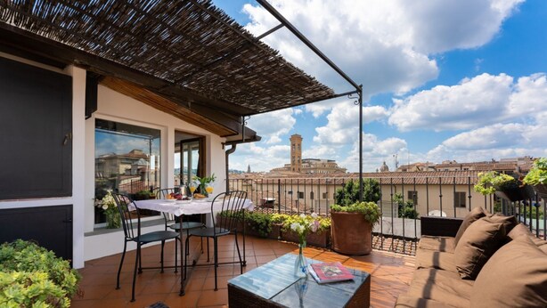 Una terrazza panoramica con tavolo, sedie, divano e piante in vaso.