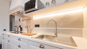 Cucina moderna con lavello in acciaio inossidabile, mobili bianchi e cappa integrata.