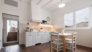 Una cucina con mobili bianchi, un tavolo da pranzo in legno e vista attraverso una finestra.