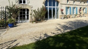 A two-story building with a large arched entrance, a gravel driveway, and a garden area with potted plants. -  BEAUTIFUL 4 BED FAMILY GITE WITH POOL-CHARENTE MARITIME. SLEEPS 10 (Mérignac)
