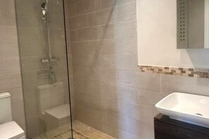 A bathroom with a glass-enclosed shower, a white sink, and a tiled wall. -  BEAUTIFUL 4 BED FAMILY GITE WITH POOL-CHARENTE MARITIME. SLEEPS 10 (Mérignac)