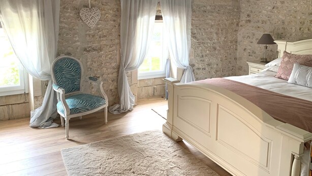 A bedroom with a bed, a chair, a nightstand, a lamp, and a window with curtains. -  BEAUTIFUL 4 BED FAMILY GITE WITH POOL-CHARENTE MARITIME. SLEEPS 10 (Mérignac)