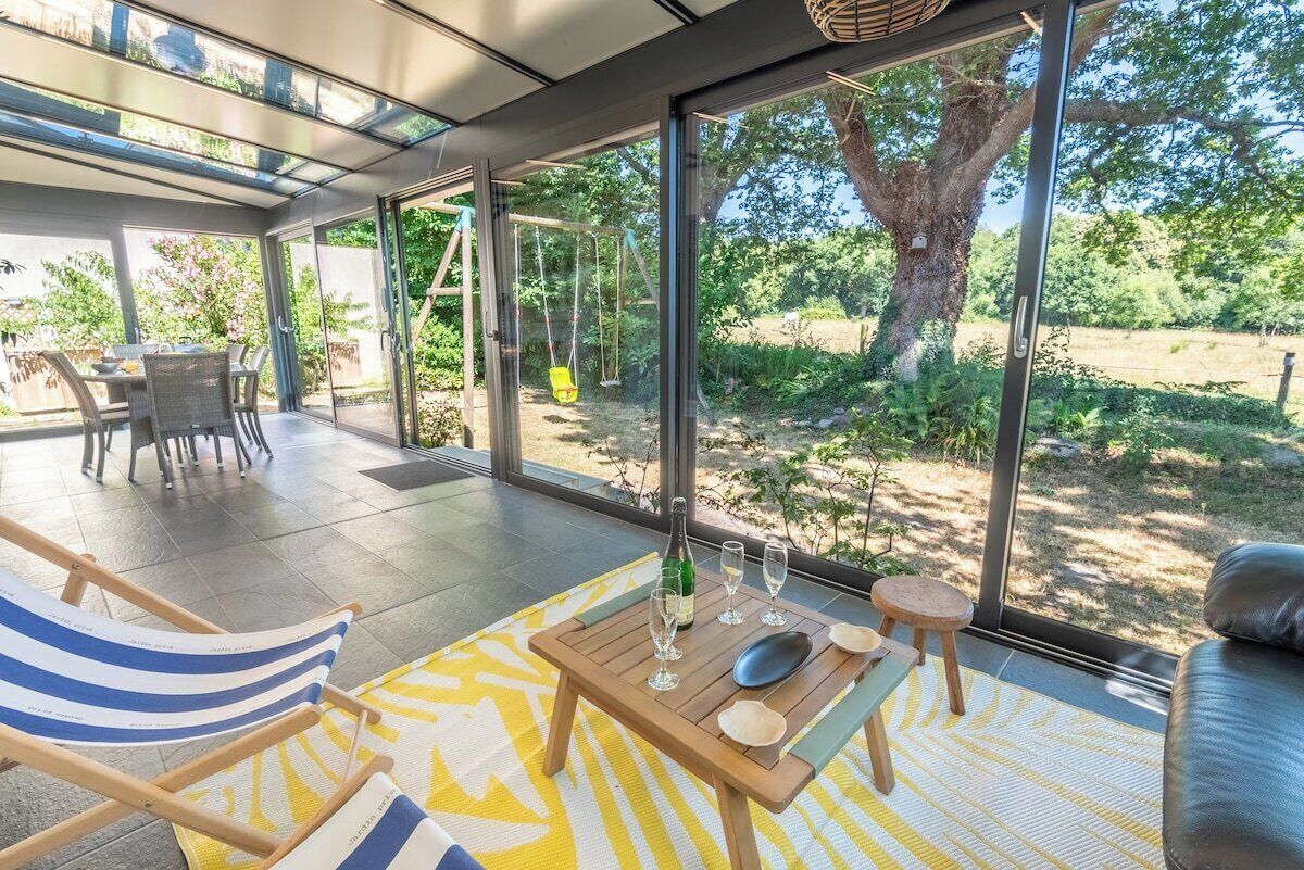 A modern outdoor seating area with a table, chairs, and a swing set.