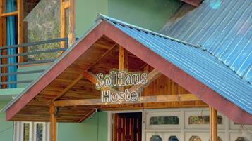 Un hostal con fachada de madera, techo de lámina corrugada y un letrero que dice 'SolHaus Hostel'.