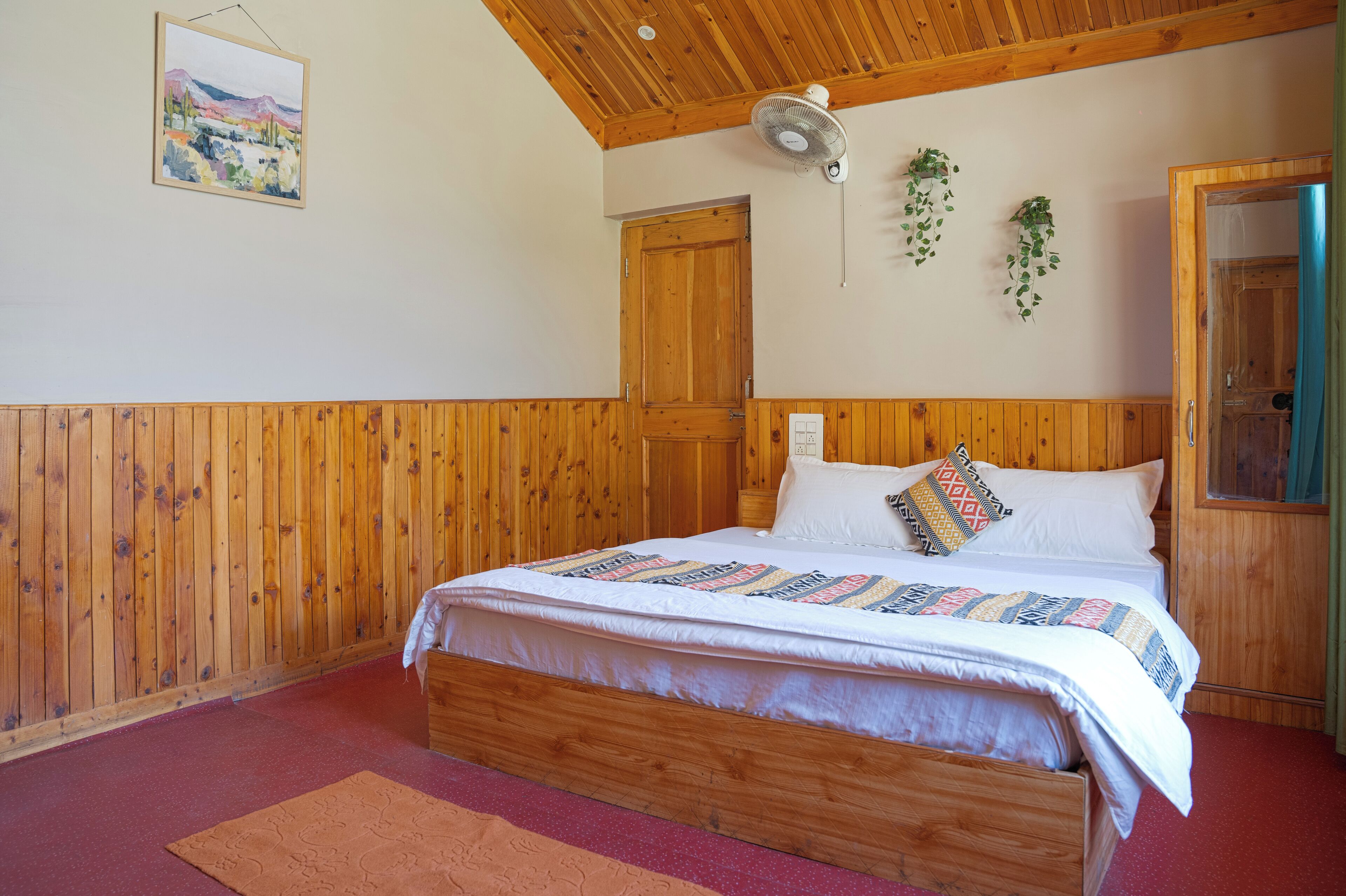 Un dormitorio con paneles de madera, una cama, un ventilador de techo y una puerta.