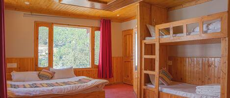 A wooden cabin bedroom with a single bed, a bunk bed, and a window with curtains.