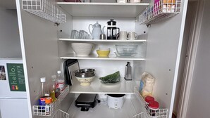 Eine kleine Küche mit weißen Schränken, einer eingebauten Mikrowelle und einer Kaffeemaschine.