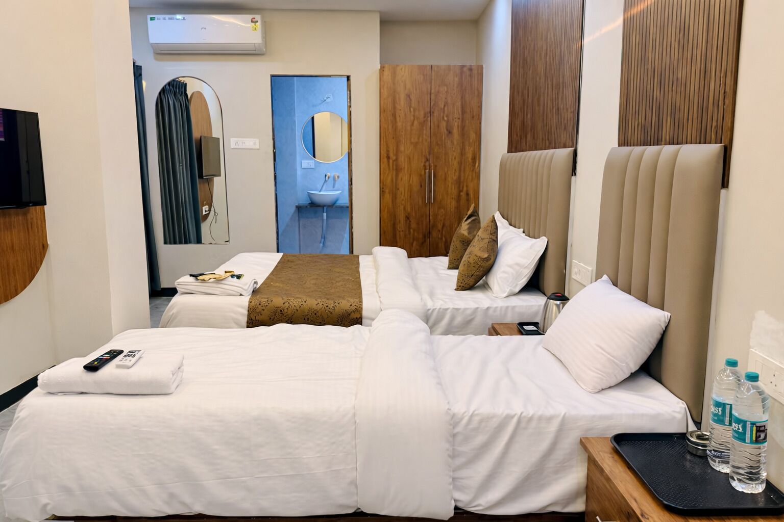 A hotel room with two beds, a bathroom, and a TV.