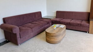 A modern living room with two brown sofas, a wooden coffee table, and a small decorative vase. - Revelon Grand Hotel (Indore)